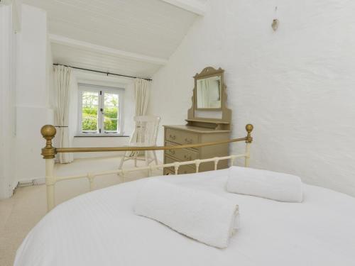 ティンタジェルにあるAyr Cottageの白いベッドルーム(ベッド1台、鏡付)