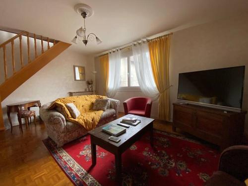 uma sala de estar com um sofá e uma televisão em Les Marmottes em Arpajon-sur-Cère