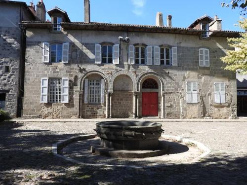 stary kamienny budynek z czerwonymi drzwiami i fontanną w obiekcie Les Marmottes w mieście Arpajon-sur-Cère