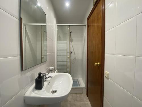 uma casa de banho branca com um lavatório e um chuveiro em R146 - Casa Residencial Estany em Calafell