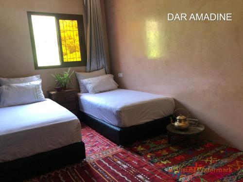 a bedroom with two beds and a table and a window at Dar Amadine in Imlil