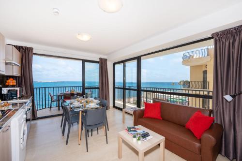 a living room with a couch and a table at Islet Promenade Seafront Apartment with large Corner Terrace by Getawaysmalta in St. Paul's Bay