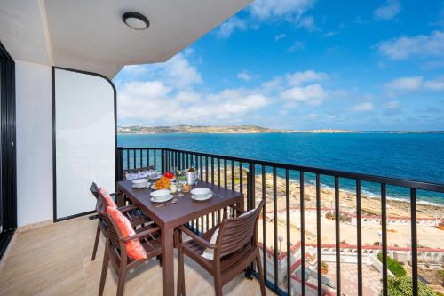 a table on a balcony with a view of the ocean at Islet Promenade Seafront Apartment with large Corner Terrace by Getawaysmalta in St Paul's Bay