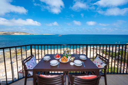 a table on a balcony with a view of the ocean at Islet Promenade Seafront Apartment with large Corner Terrace by Getawaysmalta in St Paul's Bay