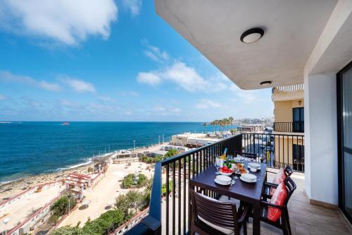 a balcony with a table and chairs and the ocean at Islet Promenade Seafront Apartment with large Corner Terrace by Getawaysmalta in St. Paul's Bay