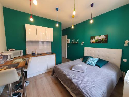 een slaapkamer met groene muren, een bed en een bureau bij "Le Petit Paradis" au Centre Ville d'Oyonnax in Oyonnax