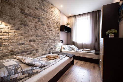 a bedroom with two beds and a brick wall at Stawowa Premium Apartment - 69 m2 with sauna and private garage in Krakow