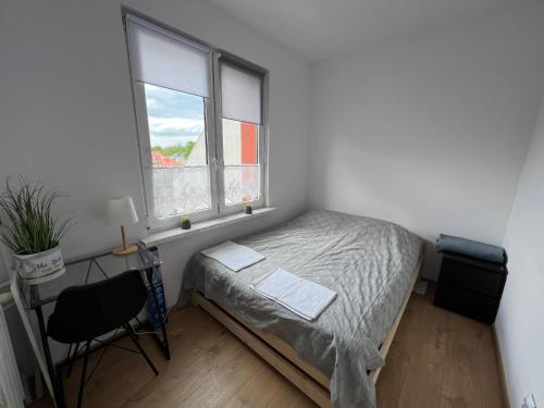a bedroom with a bed and a desk and a window at ApartmentsByMatyrafa-I in Tarnowskie Góry
