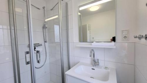 a white bathroom with a sink and a shower at Haus Polarstern Ferienwohnung Kapella in Borkum