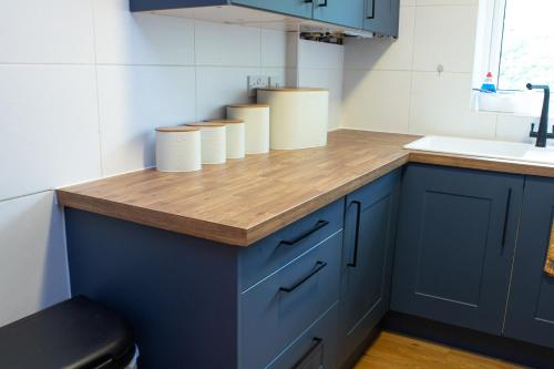 a kitchen with blue cabinets and a wooden counter top at Stylish 2Bed Apt in Leeds - Free Parking! in Headingley