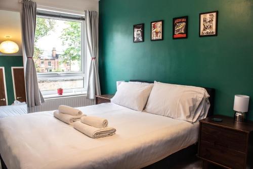 a green bedroom with a bed with towels on it at Stylish 2Bed Apt in Leeds - Free Parking! in Headingley