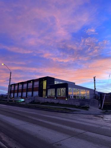 a building on the side of a street with a sunset at Hotel Costanera in Puerto Natales