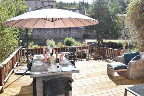 a wooden deck with a table with an umbrella at Riverside 4 bed house full of character and charm in Quillan