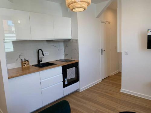 La cuisine est équipée de placards blancs et d'un four micro-ondes noir. dans l'établissement Superbe appartement, 2 couchages, proche Paris, à Bagnolet