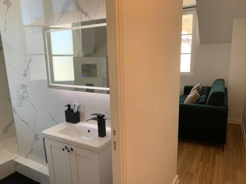une salle de bain avec un lavabo, un miroir et un canapé dans l'établissement Superbe appartement, 2 couchages, proche Paris, à Bagnolet