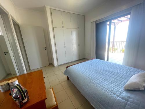 a bedroom with a bed and a table and a window at Nysa7 in Paphos City