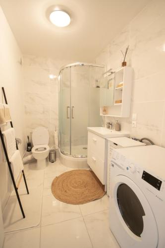 La salle de bains blanche est pourvue d'une douche et d'un lave-linge. dans l'établissement LES DUNES Studio Ideal couple,solo,famille&pro, à Vitry-sur-Seine