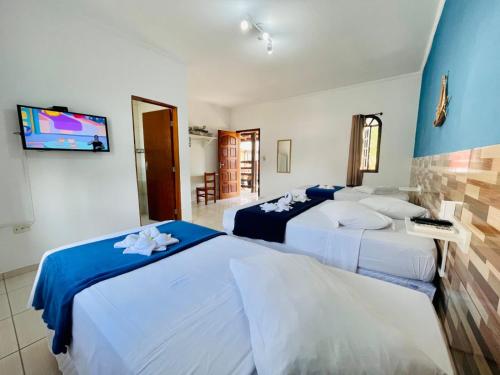 1 dormitorio con 3 camas y TV de pantalla plana en Beija Flor Pousada, en Ubatuba