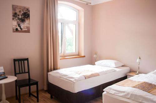 two beds in a room with a window and a chair at Przystanek Tleń in Tleń