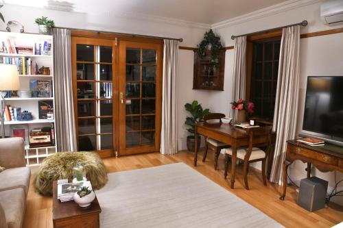 a living room with a table and a television and a desk at Forth River Cottage in Forth