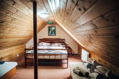 a attic bedroom with a bed and a wooden ceiling at Vila Zuzka in Stará Lesná