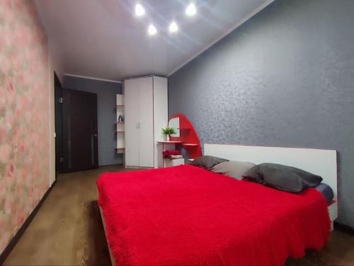 a bedroom with a red bed with a red blanket at Апартаменты 2-х комнатные в Степногорске in Stepnogorsk
