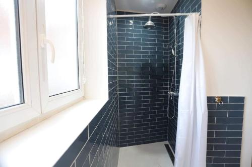een badkamer met een blauwe betegelde douche en een raam bij Le vintage 100 mètres de la gare parking gratuit in Douai