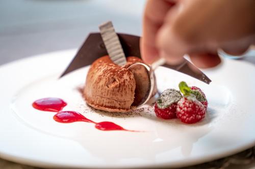 a person cutting a piece of bread on a plate with strawberries at Parc Hotel Billia in Saint Vincent