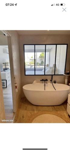 una bañera en un baño con ventana en Marina Port Camargue appontement bateau, en Le Grau-du-Roi