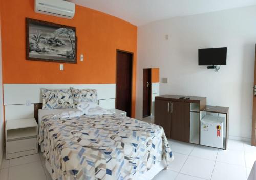 a bedroom with a bed and a flat screen tv at Pousada Solar Da Lagoa - Baixio BA in Baixio