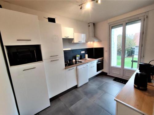 uma cozinha com armários brancos e uma grande janela em LE PHARE em Criel-sur-Mer
