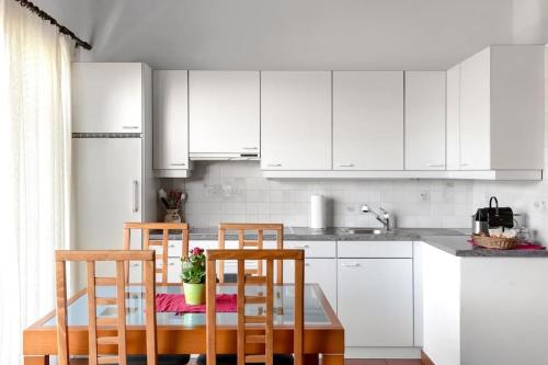 a kitchen with white cabinets and a table and chairs at Casa Ruth Brissago in Brissago