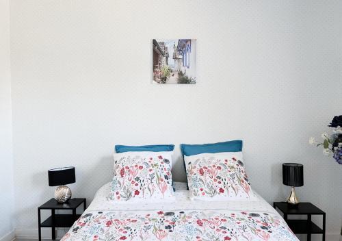 ein Bett mit zwei Kissen und einem Bild an der Wand in der Unterkunft Maison Léon in Ychoux