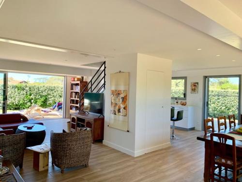 un salon avec une table, des chaises et une télévision dans l'établissement Modern Beach Villa 150m from the Atlantic surf, à Capbreton