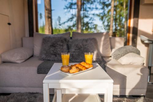 uma mesa com dois copos de sumo de laranja e uma bandeja de donuts em TaaliHomes Metsamajake - kadakasaun hinnas 