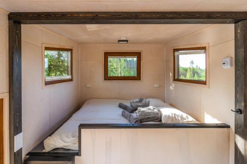 Un dormitorio pequeño en una casa diminuta con dos ventanas. en TaaliHomes Metsamajake - kadakasaun hinnas, en Soesaare