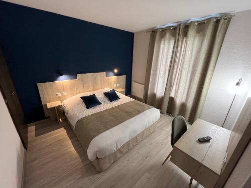 um quarto com uma cama grande e uma parede azul em Hôtel Restaurant Prunières em Aumont-Aubrac