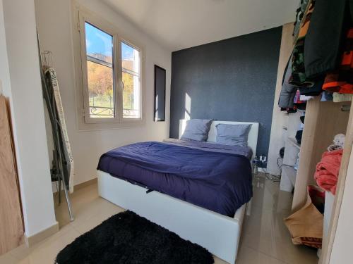 a bedroom with a bed with blue sheets and a window at 2 pièces d’exception vue Mer in Vence