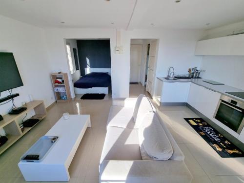 a living room with a white couch and a television at 2 pièces d’exception vue Mer in Vence