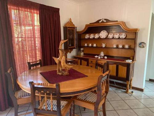a dining room with a wooden table and chairs at Home away from Home in Pretoria