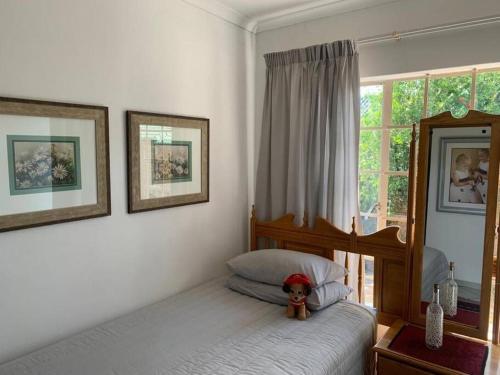un osito de peluche sentado en una cama en un dormitorio en Home away from Home, en Pretoria