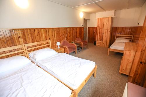 two beds in a room with wooden walls at Horská chata Medika in Horní Maršov