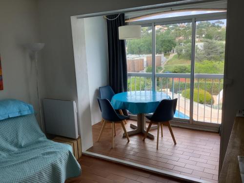 - une chambre avec une table bleue, des chaises et une fenêtre dans l'établissement Au calme dans hameau fleuri joli Studio 3 pers piscine parking wi-fi, à Vence