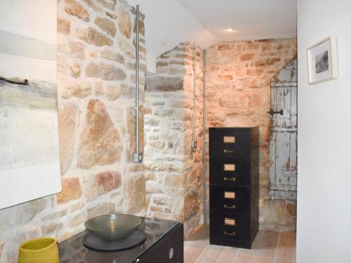 Cette chambre est dotée d'un mur en pierre et d'une armoire noire. dans l'établissement Stone Cottage, à Elgol