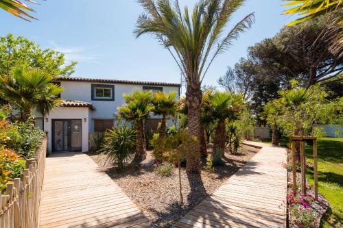 une maison avec des palmiers et une passerelle en bois dans l'établissement Mas Julia, à Vias