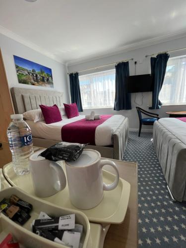 una habitación de hotel con 2 camas y una mesa con tazas en Berry Hotel, en Paignton