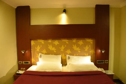 una camera da letto con letto con testiera in legno e cuscini bianchi di EVEREST PARK RESIDENCY a Tiruchchirāppalli
