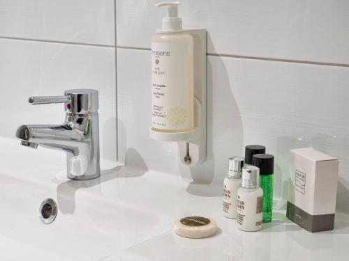 a bathroom sink with bottles of soap and a faucet at Hotel Cardinal in Spa