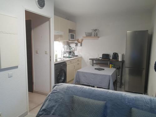 une cuisine avec un réfrigérateur et une table à l'intérieur dans l'établissement T2 avec balcon plein sud, à Lourdes
