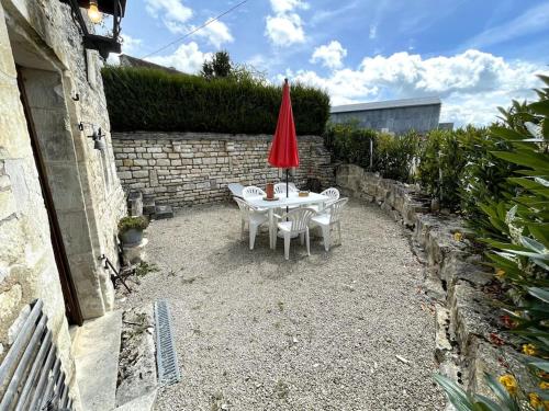 a patio with a table and a red umbrella at Maison des gardiens du château in Béru